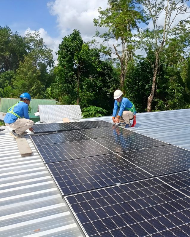 Two technicians fitting solar panels on a metal roof