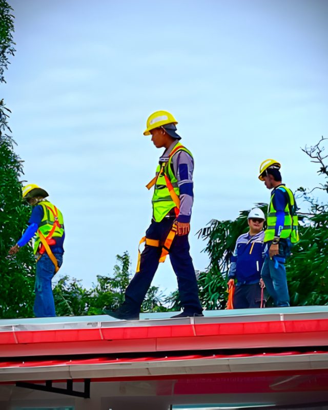 Three TAE Solar technicians in harnesses walking along a roof