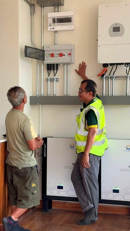 Two people at the inverter and battery installation inside the house