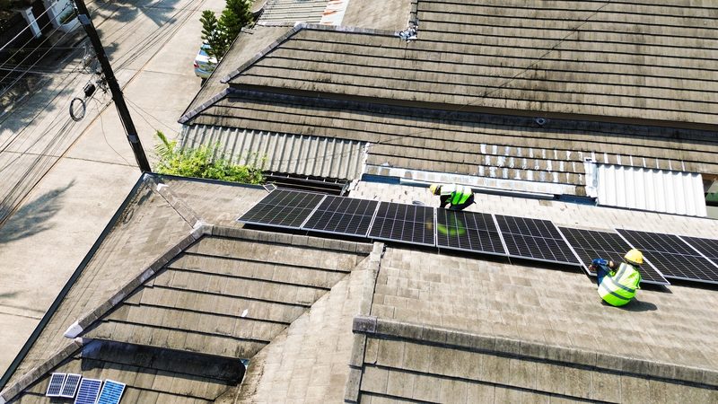 Aerial view of technicians installing panels on a large tiled roof