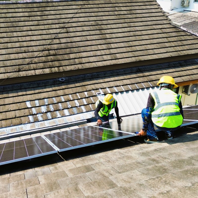Technicians installing panels on a concrete tile roof